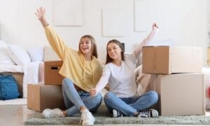 Two people taking a well-deserved break amidst cardboard boxes after a successful move into their new house.