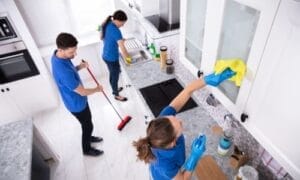 Several individuals working efficiently to clean a kitchen, demonstrating a key step in moving preparation.