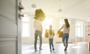 A happy family carrying boxes out of their clean and tidy house on moving day, showcasing the benefits of pre-move decluttering.