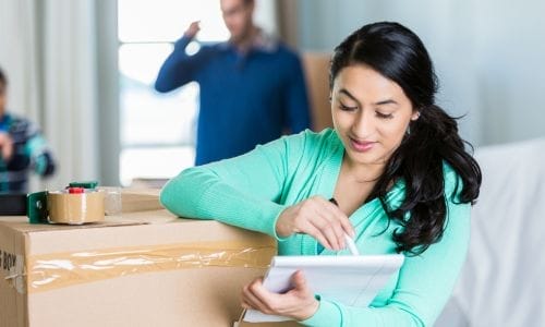 A person using an 8 week moving checklist on a laptop to plan their Edmonton relocation, with a calendar and notebook nearby. 